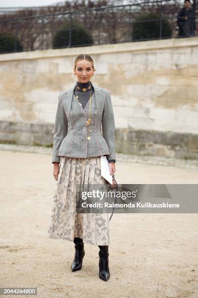 Guest wears long beige maxi skirt with grey flowers, grey turtleneck top, golden butterfly necklace and checkered grey jacket outside Dior during the...