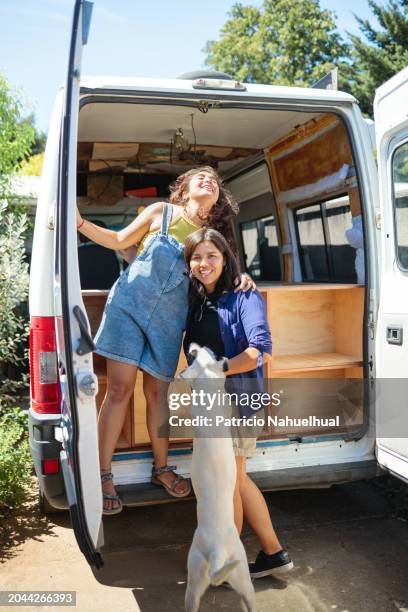 vanlife bliss: latina couple affectionately hugging and playing with their furry friend during van conversion for adventures. - wonderlust stock-fotos und bilder