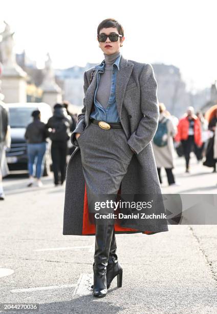 Dara is seen wearing a gray coat, jean shirt, gray turtleneck, gray skirt, black and gold belt, black knee high boots and black sunglasses outside...