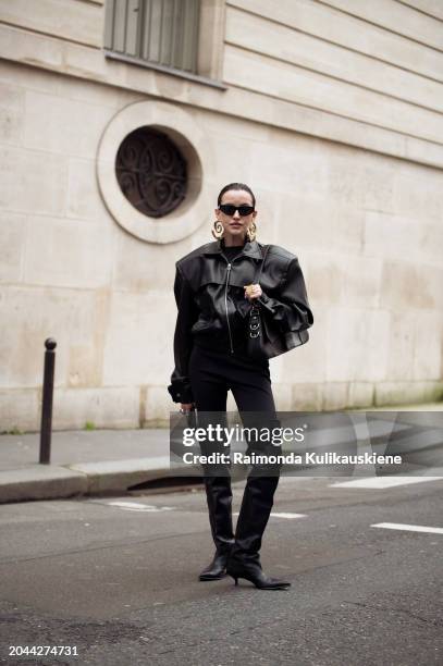 Nastya Burlaka wears black pants, black cropped leather jacket, black bag, sunglasses, and black leather long knee hight boots golden statement...