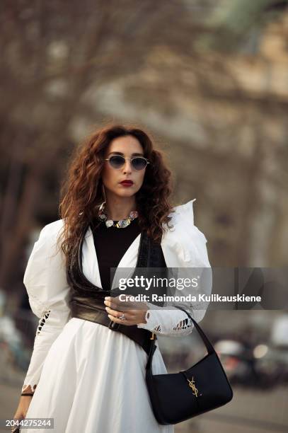 Guest wears white pants with pattern, grey top and matching jacket with a rose decoration outside Anrealage during the Womenswear Fall/Winter...