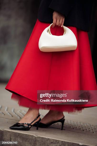 Guest wears red long skirt, black jacket and white bag outside Dawei during the Womenswear Fall/Winter 2024/2025 as part of Paris Fashion Week on...