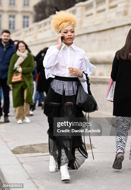 Guest is seen wearing a white button down shirt, black sheer skirt, white boots and black bag outside the Dior show during the Womenswear Fall/Winter...