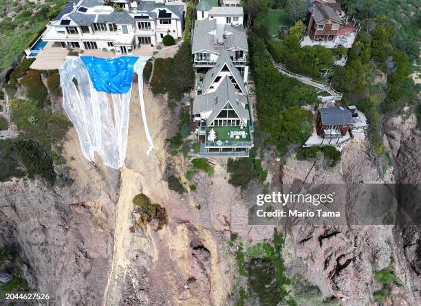 An aerial view of mansions still standing along a cliff after a portion of the cliffside tumbled to the Pacific Ocean following days of heavy rains...