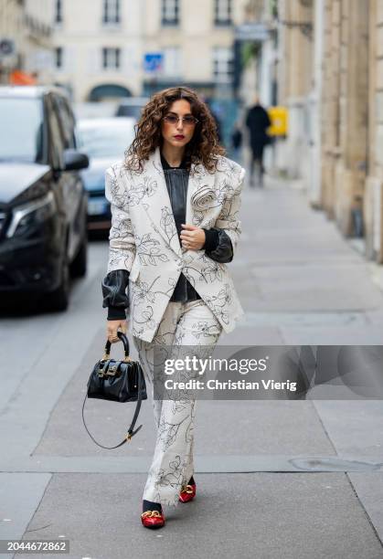 Gabriella Berdugo wears blazer with print, pants, black bag, leather jacket outside Victoria/Tomas during the Womenswear Fall/Winter 2024/2025 as...