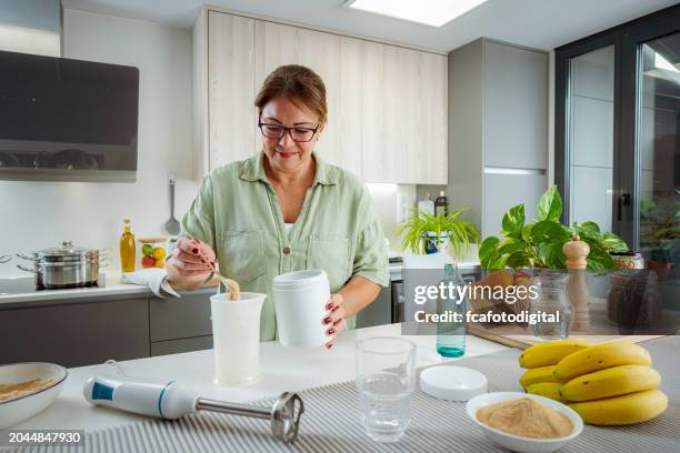 mature woman preparing meal replacement shake - proteïnedrank stockfoto's en -beelden