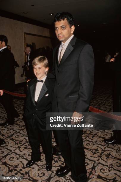 American child actor Haley Joel Osment, wearing a tuxedo and bow tie, and Indian-American film director and screenwriter M Night Shyamalan, who wears...