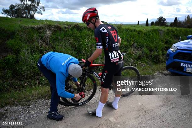 Swiss Nils Brun stops to change a wheel after a puncture during the 18th one-day classic 'Strade Bianche' cycling race between Siena and Siena,...