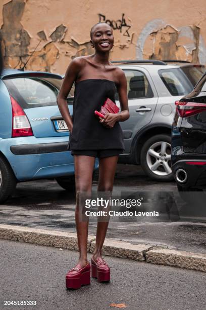 Amina Seck wears a black playsuit, red Gucci platform loafers, outside Gucci, during the Milan Fashion Week - Womenswear Fall/Winter 2024-2025 on...
