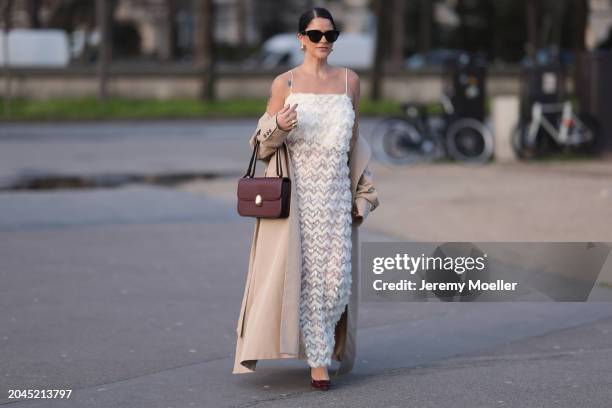 Gili Biegun seen wearing YSL black sunglasses, Bottega Veneta gold tear drops earrings, white long sheer pearl embroidered maxi dress, gold statement...