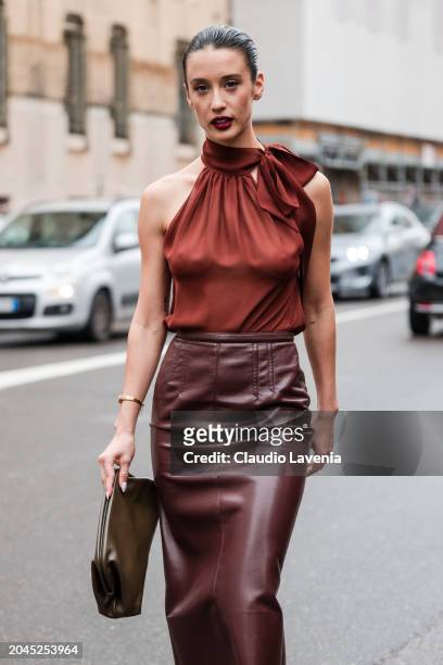 Maria Pedraza wears burnt orange top, brown leather midi skirt, olive green pouch bag, outside Philosophy, during the Milan Fashion Week - Womenswear...