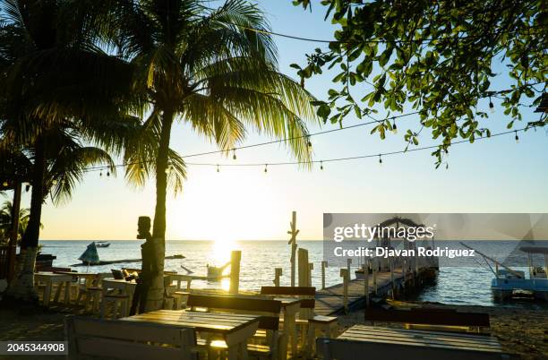 sunset in front of a beach pier in west end. - honduras stock pictures, royalty-free photos & images