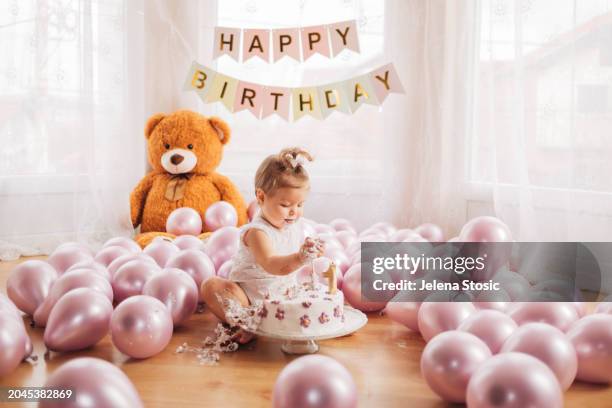 cake smash. birthday girl is trying her first birthday cake while sitting on the floor. - birthday candle number stock pictures, royalty-free photos & images