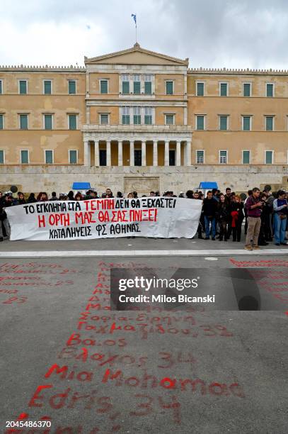 Student writes with a red paint the names and age of the 57 people killed in a train accident last year in front of the Greek parliament during a...