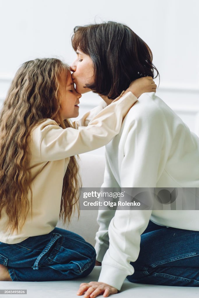Unconditional love: mom and daughter kissing and embracing on the couch