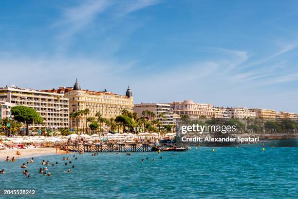 beach and luxury hotels along croisette promenade in cannes, french riviera, france - cannes stock-fotos und bilder