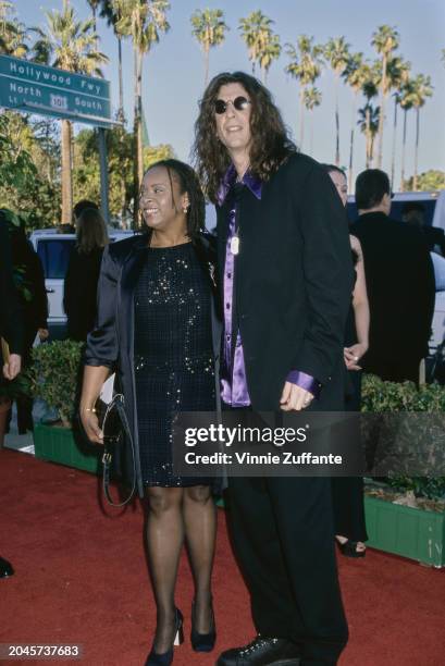American radio host Robin Quivers, wearing a black coat over a black sequin dress, and American radio host and 'shock jock' Howard Stern, who wears a...