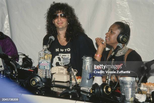 American radio host and 'shock jock' Howard Stern, wearing a black t-shirt with a gun motif and sunglasses, and his co-host, American radio host...