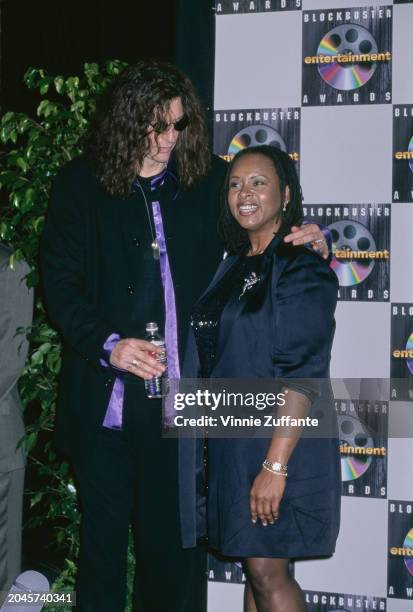 American radio host and 'shock jock' Howard Stern, wearing a black suit over a purple shirt, with American radio host Robin Quivers, who wears a...