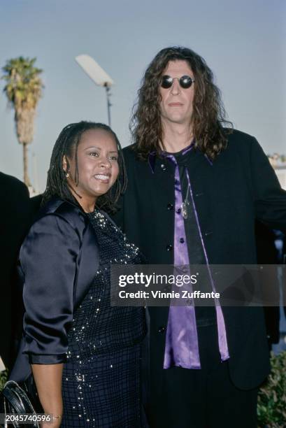 American radio host Robin Quivers, wearing a black coat over a black sequin dress, and American radio host and 'shock jock' Howard Stern, who wears a...