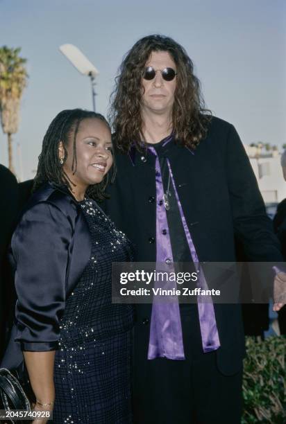 American radio host Robin Quivers, wearing a black coat over a black sequin dress, and American radio host and 'shock jock' Howard Stern, who wears a...