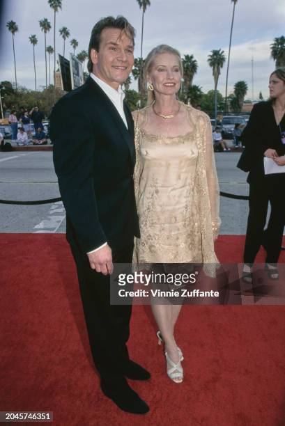 American actor, singer and dancer Patrick Swayze, wearing a black suit over a white shirt, and his wife, American dancer, choreographer and actress...