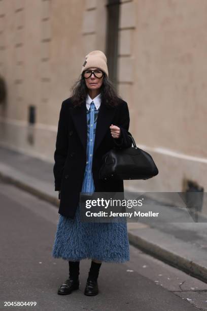 Guest seen wearing Louis Vuitton beige wool knit logo beanie, black glasses, blue / black striped print pattern buttoned shirt with white collar,...