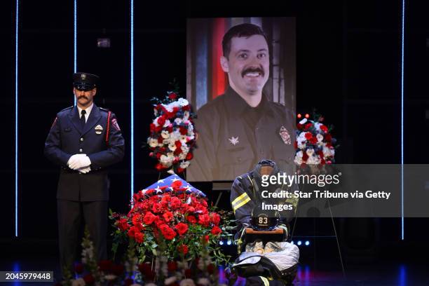 Photograph of firefighter-paramedic Adam Finseth stands over his gear during a memorial service for Finseth and Burnsville, Minn. Police officers...