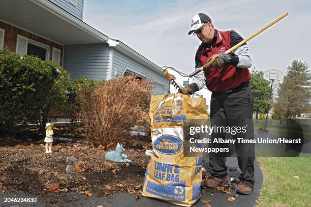 Retired Mark Mindel rakes around his bushes as he works on his list of chores on Thursday, April 17, 2014 in Malta, N.Y.