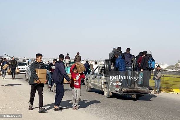 In this image grab from an AFPTV video, people carry food parcels that were airdropped from US aircrafts above a beach in the Gaza Strip, on March 2,...