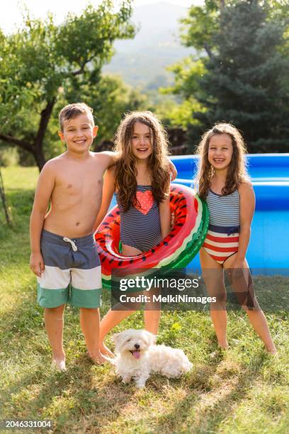 children enjoying summer in inflatable pool in the yard - boy-with-a-girl-playing-at-the-poolside stock pictures, royalty-free photos & images