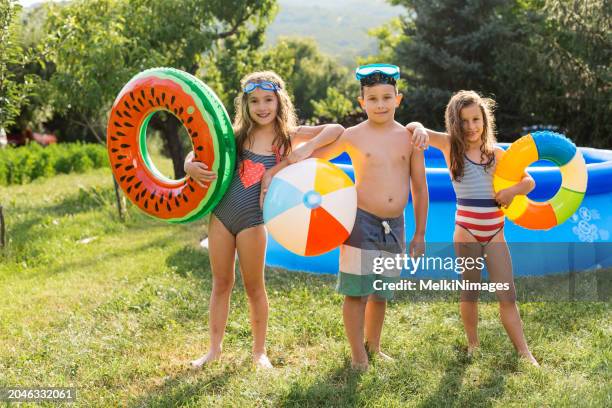 children enjoying summer in inflatable pool in the yard - boy-with-a-girl-playing-at-the-poolside stock pictures, royalty-free photos & images