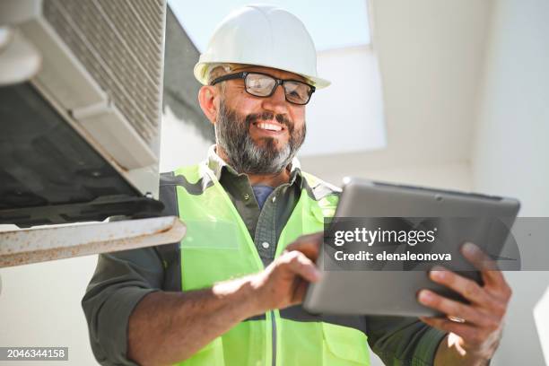 engineer repairs air conditioner - building roof repair stock pictures, royalty-free photos & images