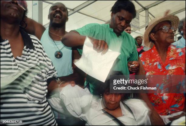 Audience members fan a woman overcome during a performance by the Pentacost Baptist Church Choir in the Gospel Tent at the New Orleans Jazz and...