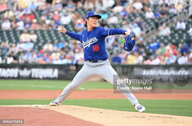 Yoshinobu Yamamoto of the Los Angeles Dodgers delivers a warm up pitch against the Texas Rangers during a spring training game at Surprise Stadium on...