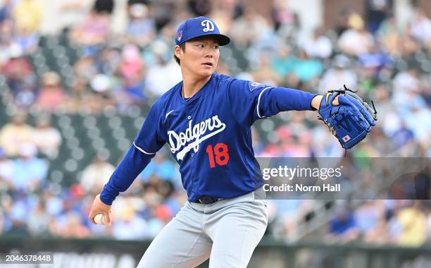 Yoshinobu Yamamoto of the Los Angeles Dodgers delivers a warm up pitch against the Texas Rangers during a spring training game at Surprise Stadium on...