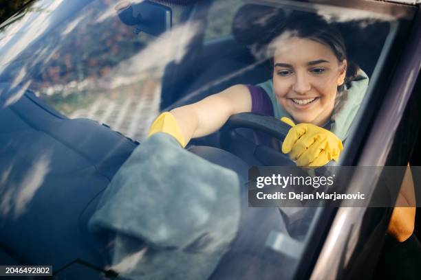 junge frau reinigt auto - windschutzscheibe innen stock-fotos und bilder