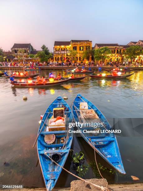riverbank of hoi an at night with vietnamese traditional houses and wooden rowing boats decorated with paper lanterns on the river and the quays, old town of hoi an - unesco world heritage site - quang nam province - central vietnam. - hoi an stockfoto's en -beelden