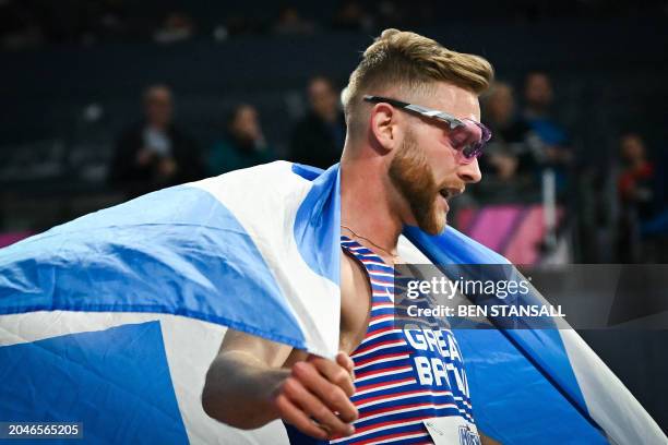 First-placed Britain's Josh Kerr celebrates with the Scottish flag after winning the Men's 3000m final during the Indoor World Athletics...