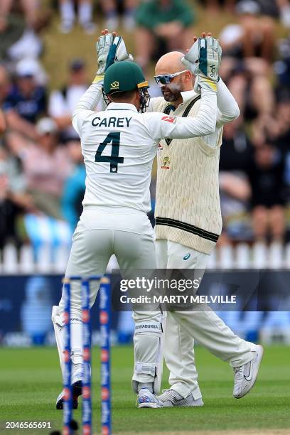 Australia's Nathan Lyon with teammate wicketkeeper Alex Carey celebrate New Zealand's Rachin Ravindra being caught during day four of the 1st...