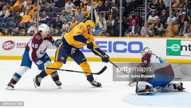 Alexandar Georgiev of the Colorado Avalanche makes a save against Yakov Trenin of the Nashville Predators as Samuel Girard defends during an NHL game...