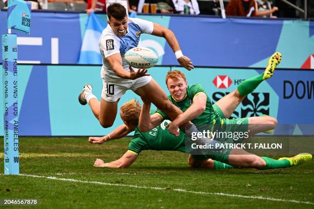 Argentina's Tobias Wade passes the ball as he is tackled by Ireland's Connor O'Sullivan and Gavin Mullin during the 2024 HSBC Rugby Sevens LA...