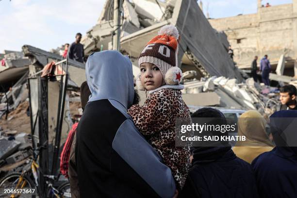 Palestinian child carried by a man looks on as people sift through rubble of the Abu Anza family home destroyed in an overnight Israeli air strike in...