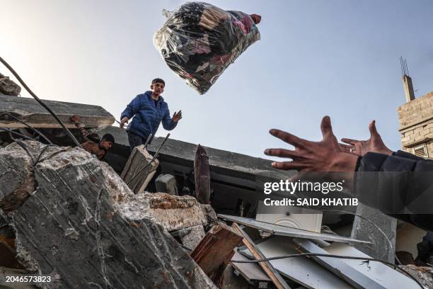 Palestinian men salvage clothes found amid the rubble of the Abu Anza family home destroyed in an overnight Israeli air strike in Rafah in the...