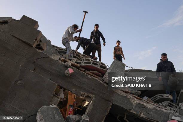 Palestinian men search through the rubble of the Abu Anza family home destroyed in an overnight Israeli air strike in Rafah in the southern Gaza...