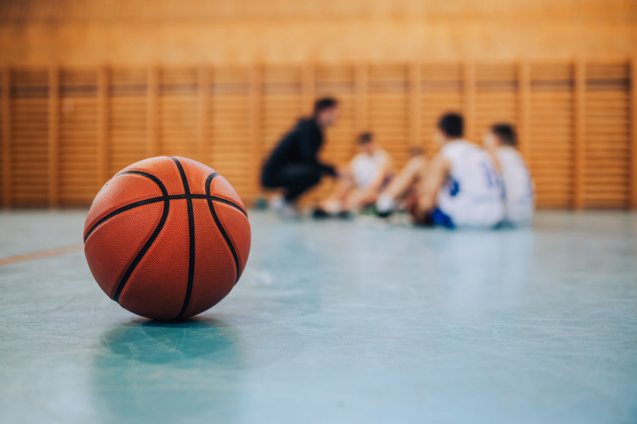 A basketball on court with junior team in blurry background. A basketball on court with junior team in blurry background.