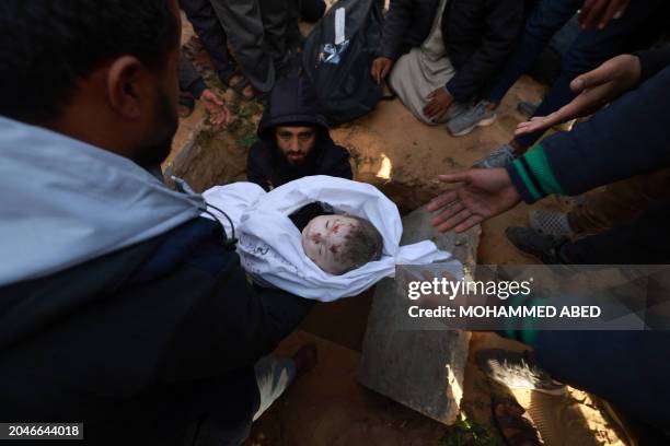 Graphic content / Men lower the bodies of twin babies Naeem and Wissam Abu Anza to their grave, after they were killed in an overnight Israeli air...