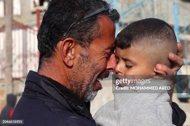 Palestinian man holds a child as he mourns the death of twin babies Naeem and Wissam Abu Anza, killed in an overnight Israeli air strike, during...
