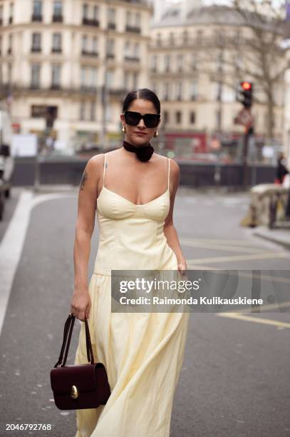 Gili Biegun wears long yellow maxi dress, burgundy bag, matching burgundy neck accessory rose or flower and sunglasses outside Dries Van Noten during...