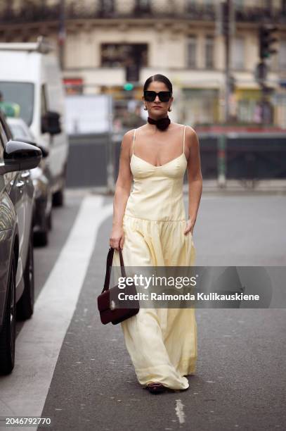 Gili Biegun wears long yellow maxi dress, burgundy bag, matching burgundy neck accessory rose or flower and sunglasses during the Womenswear...